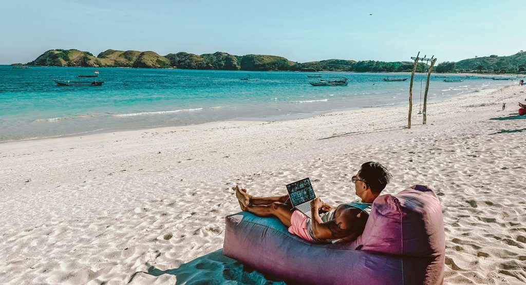 Man working at the beach with a laptop.